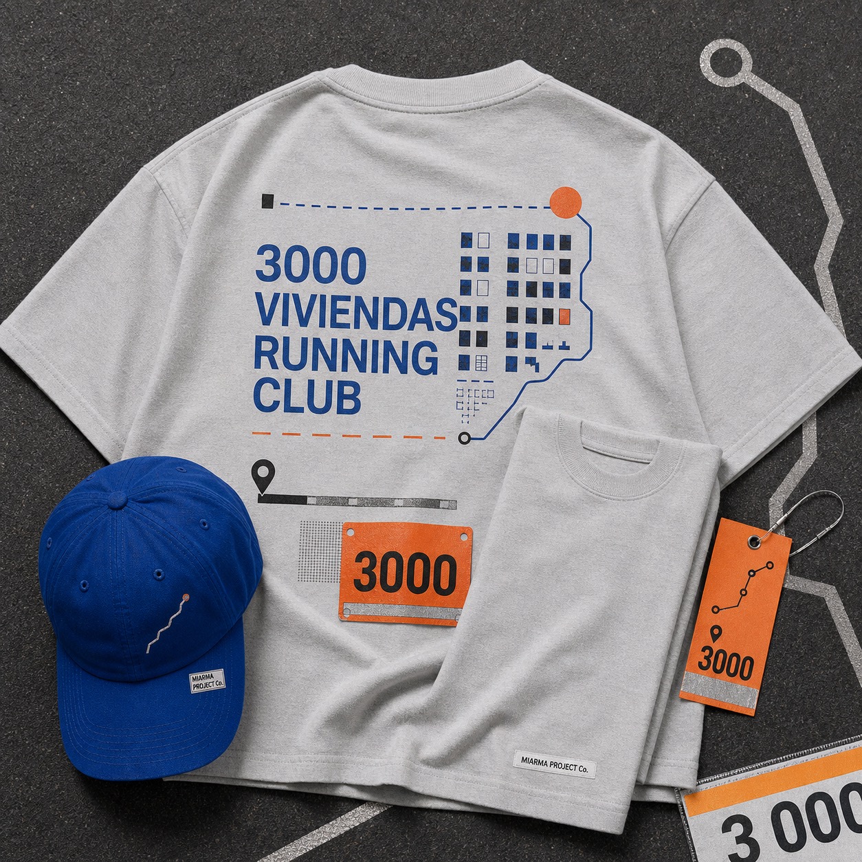Ice-gray 3000 Viviendas Running Club tee folded beside a cobalt running cap with a small MIARMA PROJECT Co. label.