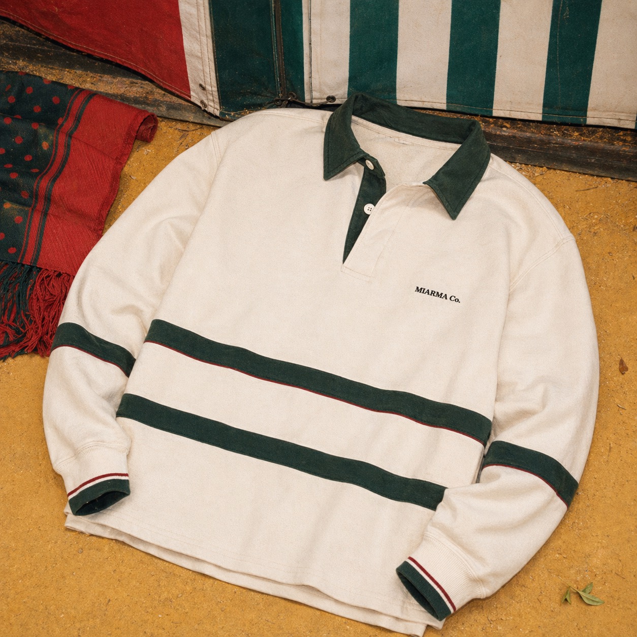 Off-white rugby shirt with green collar, feria-inspired striped scarf, and small chest text.
